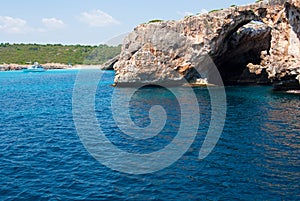 Natural arch and recreational boat at Cala Antena