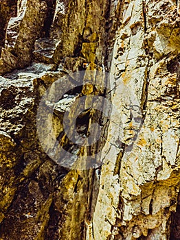 Natural background. Closeup edged shabby cliff cracks. Gray-brown stone rock texture of mountains. Vintage and faded