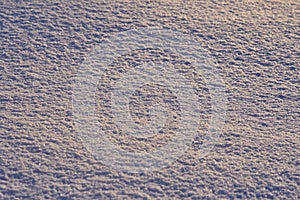 Natural background - ice surface of snow illuminated by the rays of the evening sun.