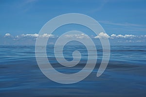 Natural background scene of gradient blue sky horizon and low raining white cloud above deep blue sea moving water ripple