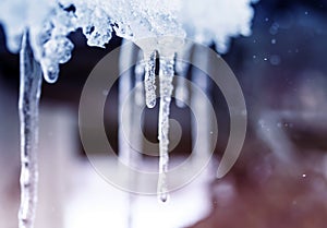 Natural background with shiny transparent icicles hanging from the roof on a spring Sunny day