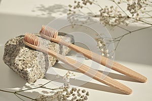 Natural bamboo toothbrush on a white background with a decor of natural stone and flowers. Plastic free Essentials, dental care.
