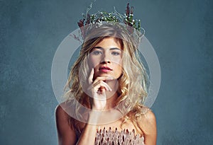 So natural, so beautiful. a young woman posing with flowers in her hair against a blue background.