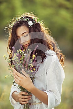 Natural beauty girl with bouquet of flowers outdoor in freedom enjoyment concept. Portrait photo