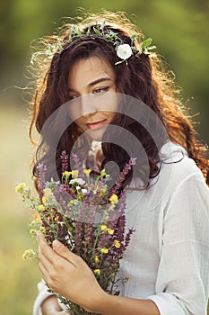 Natural beauty girl with bouquet of flowers outdoor in freedom enjoyment concept. Portrait photo