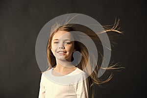 Natural beauty. Girl kid long hair flying in air, black background. Child with natural beautiful healthy hair. Quick