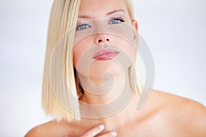 Natural beauty personified. Poised young woman touching her skin against a white background.