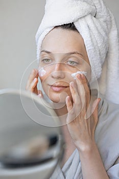 natural beauty and skin care, beautiful young caucasian woman applies cream on her face, beauty of face and body, skin