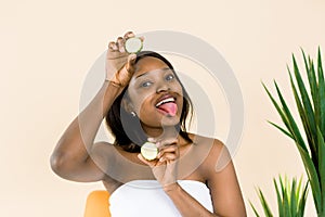 Natural Beauty, skin care treatments, Pretty African Woman showing tongue and holding cucumber slices, fresh clean skin