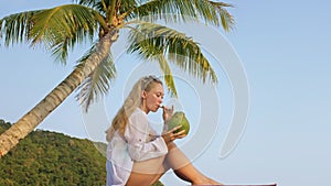 Natural beauty woman is enjoy drink tropical cocktail from fresh green coconut. Woman spends her holidays on tropical