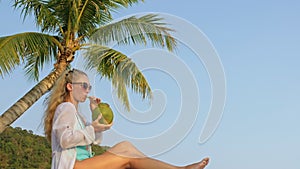 Natural beauty woman is enjoy drink tropical cocktail from fresh green coconut. Woman tourist spends her holidays on