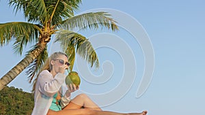 Natural beauty woman is enjoy drink tropical cocktail from fresh green coconut. Woman tourist spends her holidays on