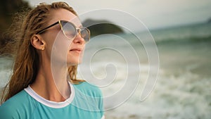 Natural beauty woman walking and relax on beach. Warm golden sunset. Woman with birthmark in blue swimsuit and