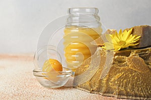 Natural beeswax blocks, flower and jar of honey on color textured table, closeup. Space for text