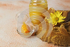 Natural beeswax blocks, flower and jar of honey on color textured table, closeup. Space for text