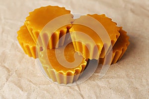 Natural beeswax cake blocks on parchment paper, closeup