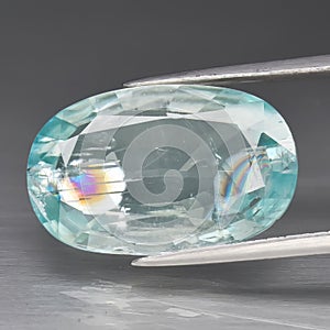 Natural blue zircon gemstone on gray background