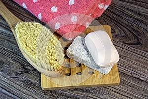Natural body brush, terry towel, soap and pumice. Hygiene supplies for bath and spa treatments on a wooden background