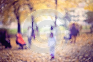 Natural bokeh background of people walking in an autumn park.