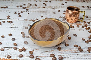 Natural bowl with ground coffee on white wooden table with organic coffee grains and espresso cup