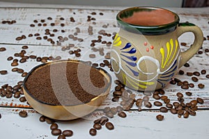 Natural bowl with ground coffee on white wooden table with organic coffee grains and Mexican cup with colorful decoration