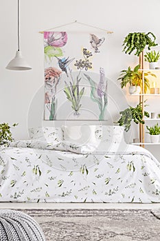 Natural bright bedroom interior with a comfortable bed dressed in organic cotton white linen with green print. Flowers and birds p