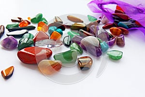 Natural bright coloured semi precious gemstones and gems with a bag on white background