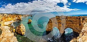 Natural caves at Marinha beach, Algarve Portugal. Rock cliff arches on Marinha beach and turquoise sea water on coast of Portugal