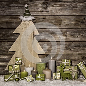 Natural christmas decoration in green and brown on wooden background with presents and candles.
