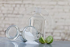 Natural cleaning products, including sodium bicarbonate, invert jar, baking soda, lemon, vinegar,on grey table on old