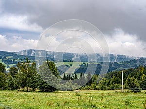 Natural cloudy misty mountain ladscape, meadow and forest