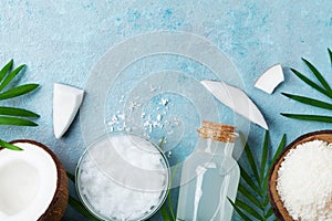 Natural coconut products for spa, cosmetic or food ingredients. Oil, water and shavings on blue table top view. Flat lay.