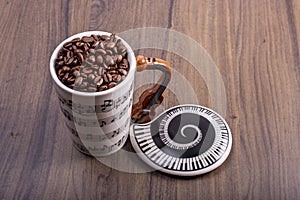 Natural coffee beans in an artistic musical cup. Music notes painted on the cup with a cello shaped handle and a plate with piano