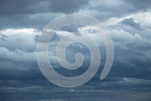 Natural color dramatic dark blue cloudy sky with wavy rippling clouds aligned above horizon, taken with wide angle 35 mm lens