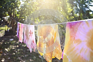 Natural color dye t-shirt hanging on plastic rope at the garden