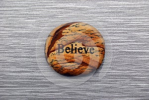 Natural colored Believe mood stone on gray background