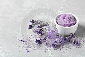 Natural cosmetic oil, bath salt, scrub and lavender flowers on grey marble table