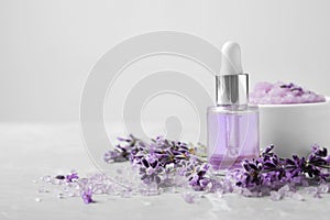 Natural cosmetic oil, bath salt, scrub and lavender flowers on grey marble table