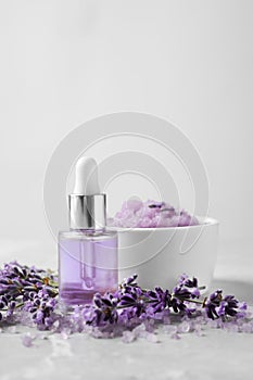 Natural cosmetic oil, bath salt, scrub and lavender flowers on grey marble table