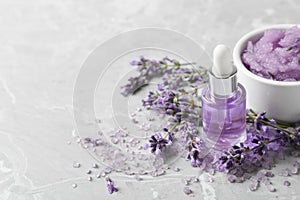 Natural cosmetic oil, bath salt, scrub and lavender flowers on grey marble table