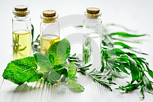 Natural cosmetic oil with fresh rosemary and mint on light wooden table background