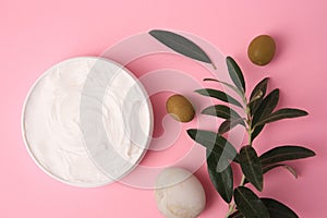 Natural cosmetic. Olive cream, pebble stone and ingredient on pink background, flat lay