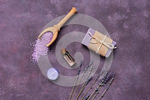 Natural cosmetic products with lavender. Soap, oil, salt, cream and dried lavender. Purple grunge background. Top view, flat lay