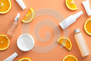 Natural cosmetic with Vitamin C. White bottles mockups, jar of moisturizer, sliced orange top view