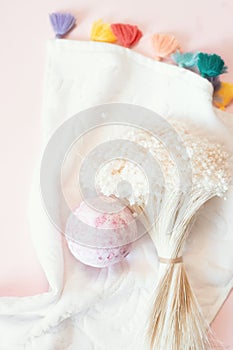 Natural cosmetics. Bath bomb, flowers and towel on pink pastel background