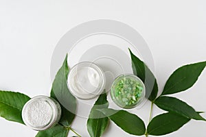 Natural cosmetics cream, sea salt with leaves for homemade bath spa white table background for text top view mock up