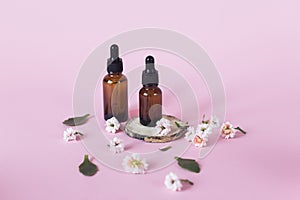 Natural cosmetics for face, body and hair care. Group of objects: glass bottles on a pink background with liquids or oil, near