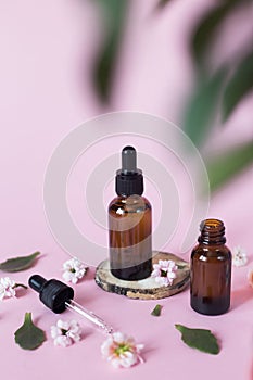 Natural cosmetics for face, body and hair care. Group of objects: glass bottles on a pink background with liquids or oil, near