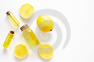 Natural cosmetics. Lemon essential oil near halfs os lemons on white background top view closeup space for text