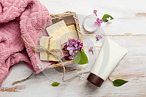 Natural cosmetics with lilac flowers. Set of cream and towel rolls.